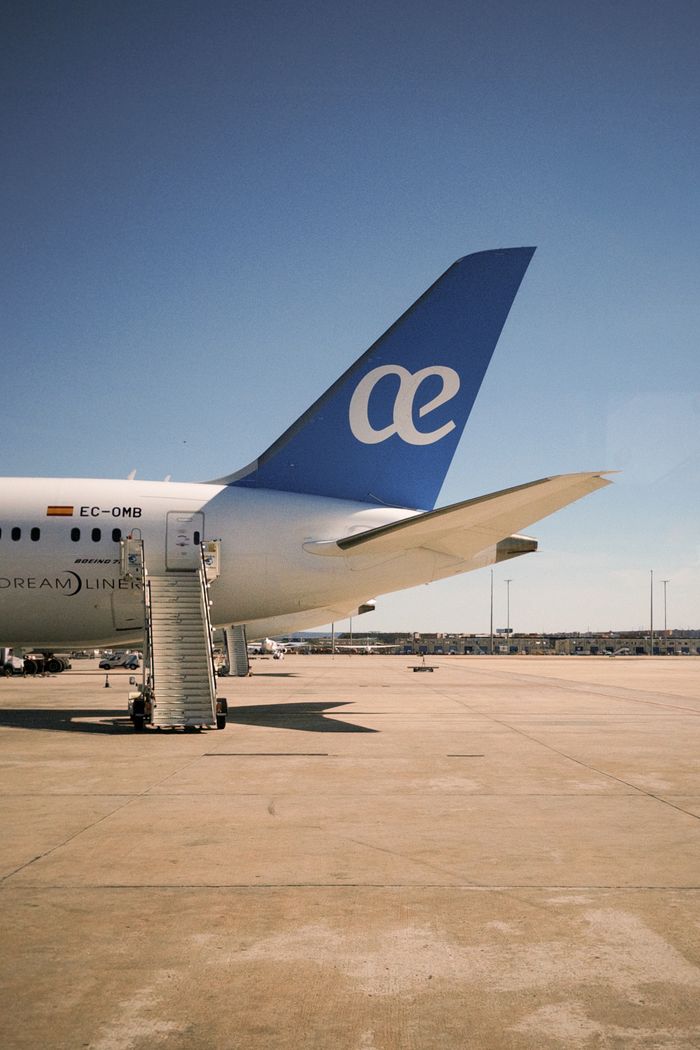 A commercial airplane parked on a tarmac with a clear blue sky in the background. Ideal for travel-related themes.
